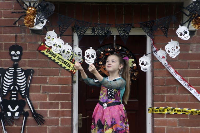 Talulah Hudson, eight, adjusts Halloween decorations outside her home in Woodlesford, Leeds (Danny Lawson/PA)