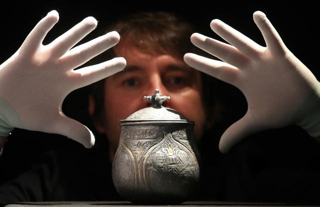 Man with hands over metal vessel