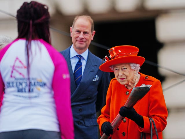 Queen Elizabeth II passes her baton to the baton bearer, British parasport athlete Kadeena Cox, at the launch of the Queen’s Baton Relay for the 2022 Birmingham Commonwealth Games