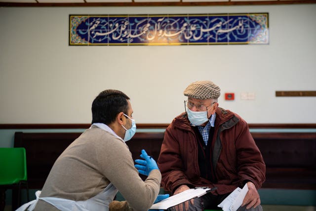 A member of the public is spoken to by a volunteer before receiving an injection of the Oxford/AstraZeneca coronavirus vaccine at the Al Abbas Mosque, Birmingham (Jacob King/PA)