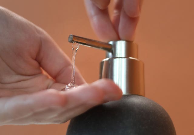 A person squeezing gel into their hands