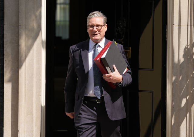 Prime Minister Keir Starmer walking out of a door holding two files