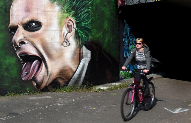 A woman cycles past a mural of Keith Flint in Peterborough