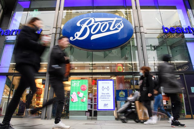 People walk past a Boots store