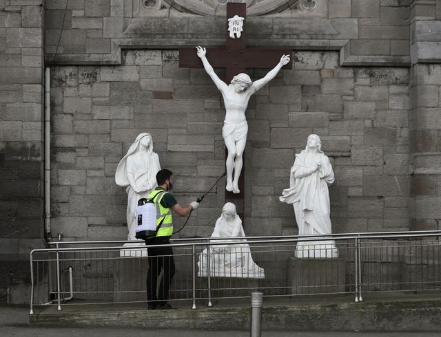 A man spraying disinfectant at a statue of the crucifixion of Jesus in Dublin on Good Friday. 