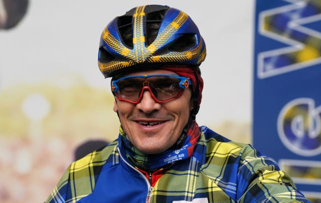 Rob Wainwright smiling while wearing cycling helmet and tartan clothing