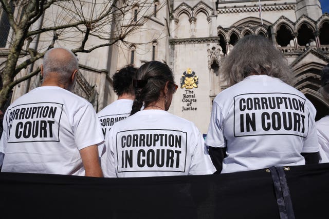 Protesters outside the Royal Courts of Justice wearing T-shirts that say 'corruption in court' on them