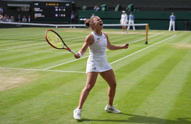 Jasmine Paolini celebrates with her arms outstretched and her fists clenched