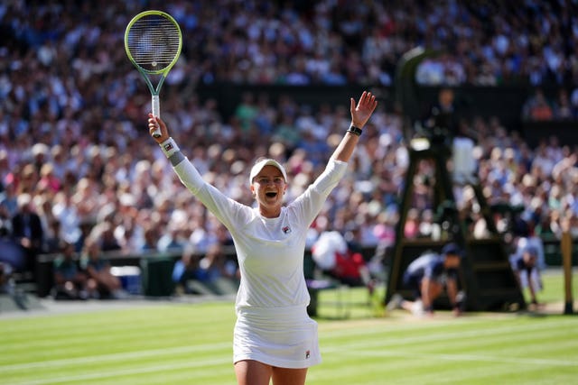 Barbora Krejcikova holds her arms and racket up in celebration