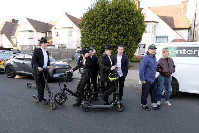 Members of the Jewish community gather near the scene in Golders Green