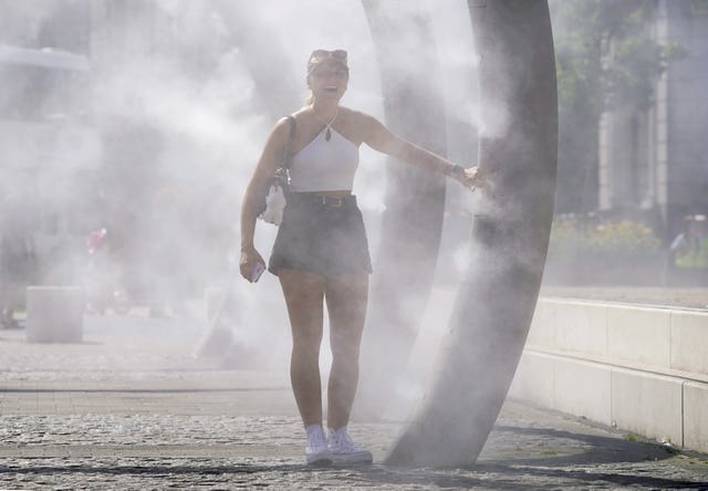 A woman pauses inside a water feature in Dover that sprays a fine mist to people walking through 