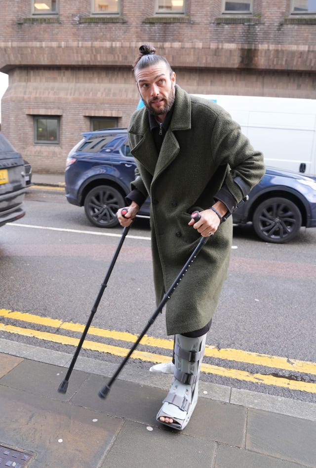 Andy Carroll pictured outside court, wearing a foot brace and using crutches