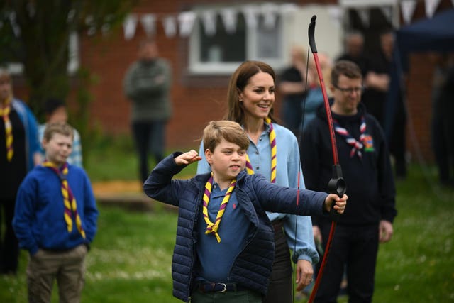 Prince George, watched by the Princess of Wales, tries archery while joining volunteers to help renovate and improve the 3rd Upton Scouts Hut in Slough 