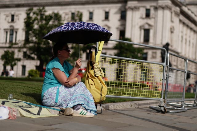 A pedestrian shelters under an umbrella in Parliament Square in London