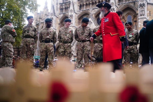 Former members of the military and cadets look at messages and crosses on display at the Field of Remembrance ahead of a service at Westminster Abbey in London