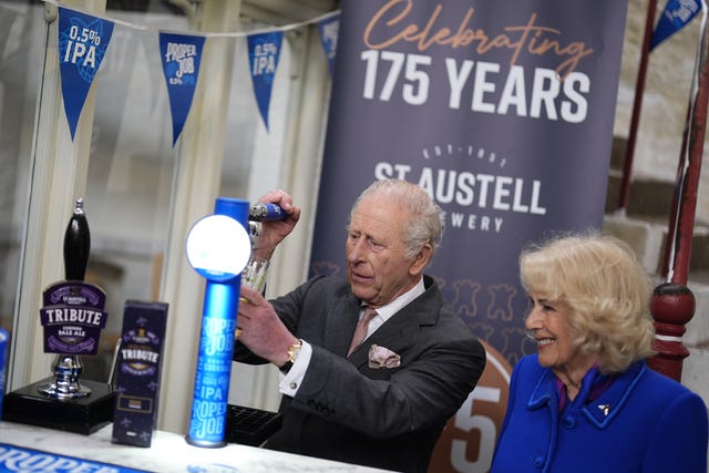 The King pulls a pint of beer, while the Queen watches on