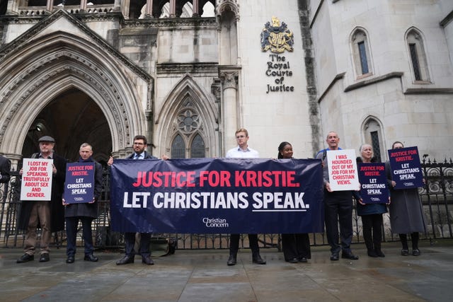 Protesters hold a banner out the High Court