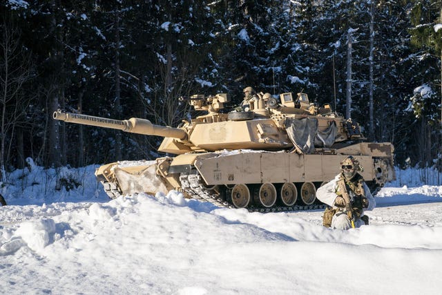 American Abrams tanks pass British soldiers during exercises