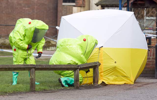 Personnel in hazmat suits securing a tent covering a bench in The Maltings shopping centre in Salisbury