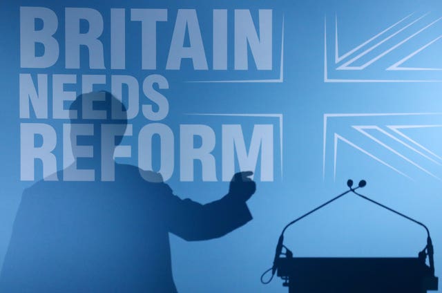 Nigel Farage's shadow falls across a blue backdrop reading Britain Needs Reform