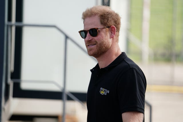 Prince Harry in a black polo and sunglasses