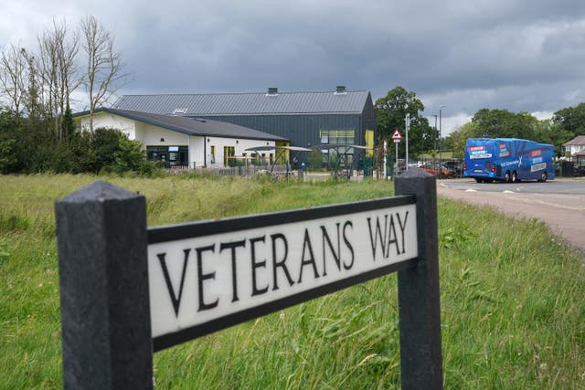 A road sign reading Veterans Way with a blue Conservative Party campaign bus in the distance 
