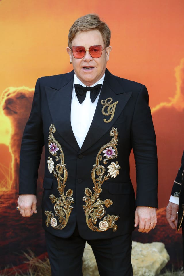 Sir Elton John, wearing an embroidered black dinner jacket