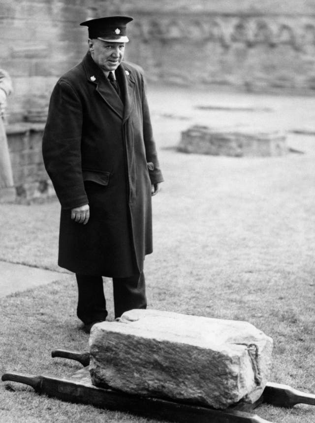 Black and white photo of a policeman next to the Stone of Destiny, which is on the ground