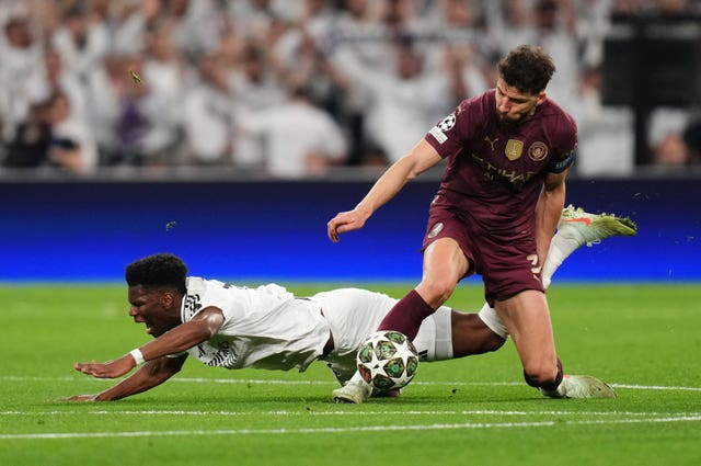 Manchester City's Ruben Dias wins the ball in a challenge with Aurelien Tchouameni 