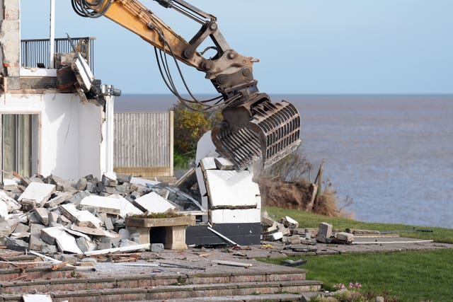 The arm of a digger being used to demolish a house