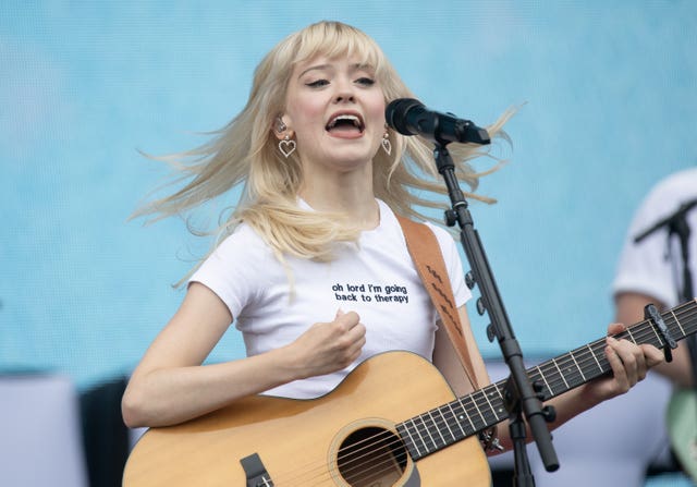 Maisie Peters performing with guitar