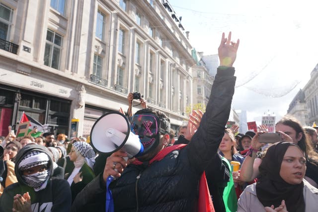 A masked supporter shouts through a megaphone during the march