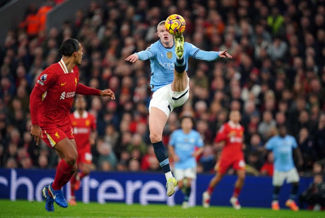 Erling Haaland, with his arms by his side, jumps to control the ball with his left foot