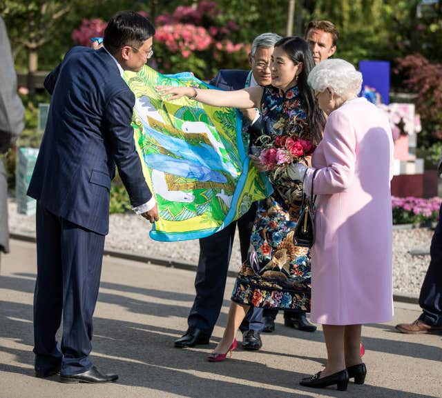 The Queen is presented with a Chinese silk scarf depicting two whales after she looked at the Chinese show garden (Richard Pohle/Times/PA) 