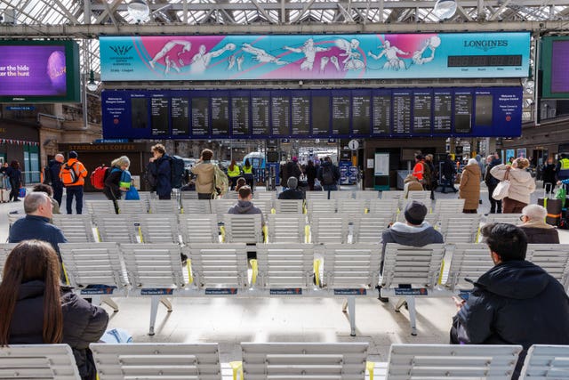 View of passengers seated and standing in front of the main departures board at Glasgow Central