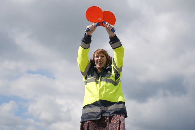 Angela Rayner holds two red paddles in the air while wearing a hi-vis jacket