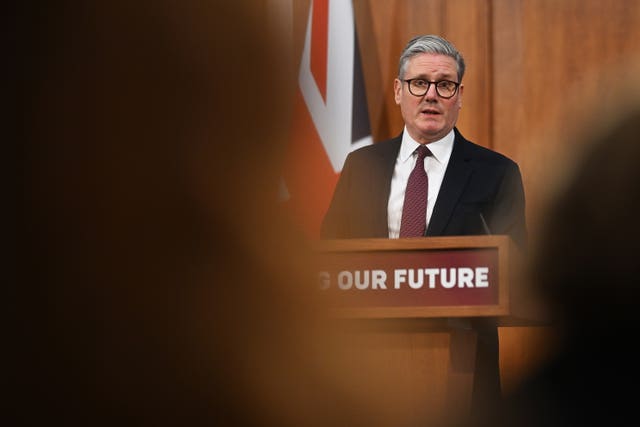 Sir Keir Starmer seen between the heads of his audience, while he speaks from a lectern