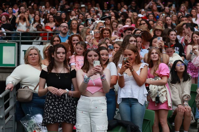 Fans in the audience hold up phones as they watch Taylor Swift