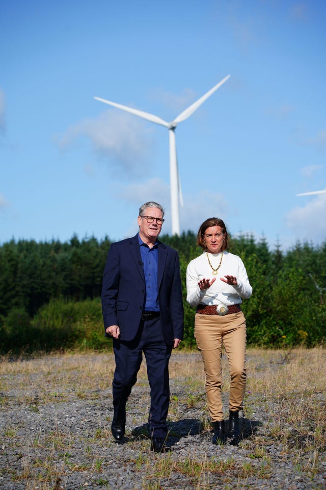 Sir Keir Starmer and Eluned Morgan walk together with a wind turbine in the background