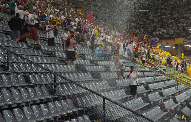 Fans shelter from the rain during the 24-minute delay