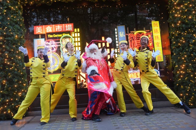 A man dressed as Santa flanked by four people dressed in yellow as bellboys, outside Selfridges