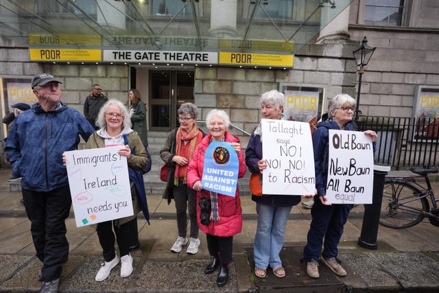 People holding anti-racism and pro-immigration posters
