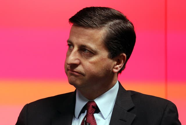 Head and shoulders photo of Douglas Alexander looking to the side, in front of a red and orange background