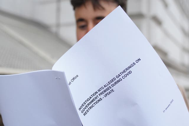 A man looks at a copy of the Sue Gray report