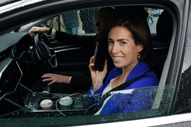Hildegarde Naughton holding a phone to her ear and smiling while sitting in the passenger seat of a car
