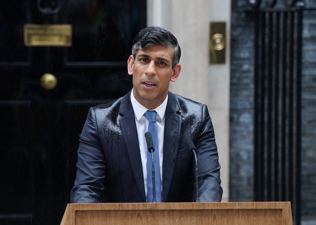A rain-drenched Rishi Sunak speaking from behind a podium in Downing Street