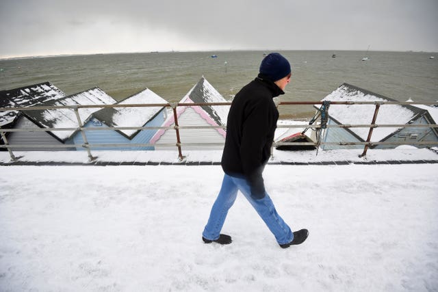 A man walks on the snow-covered seafront at Thorpe Bay, Essex
