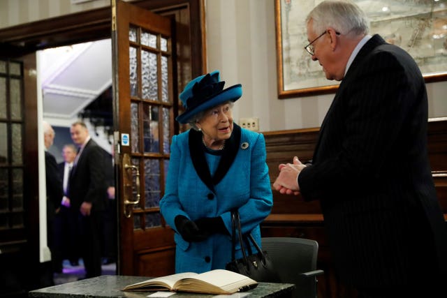 The Queen signs the visitors' book during a visit to the new headquarters of the Royal Philatelic Society in London