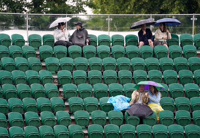 Spectators shelter under umbrellas in the stands at Wimbledon