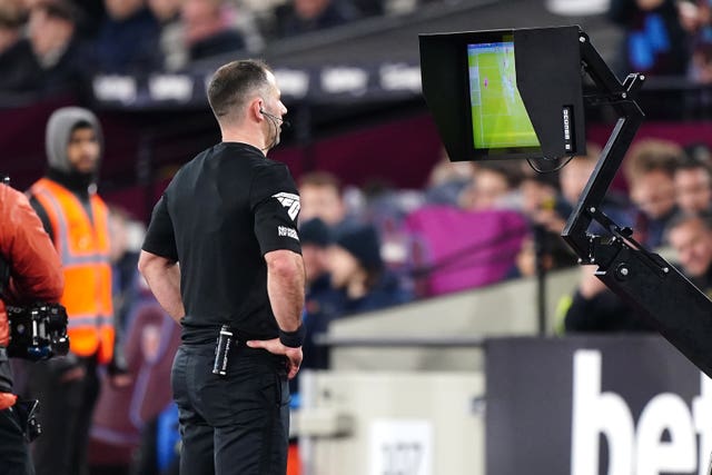 Referee Tim Robinson views the on pitch VAR monitor